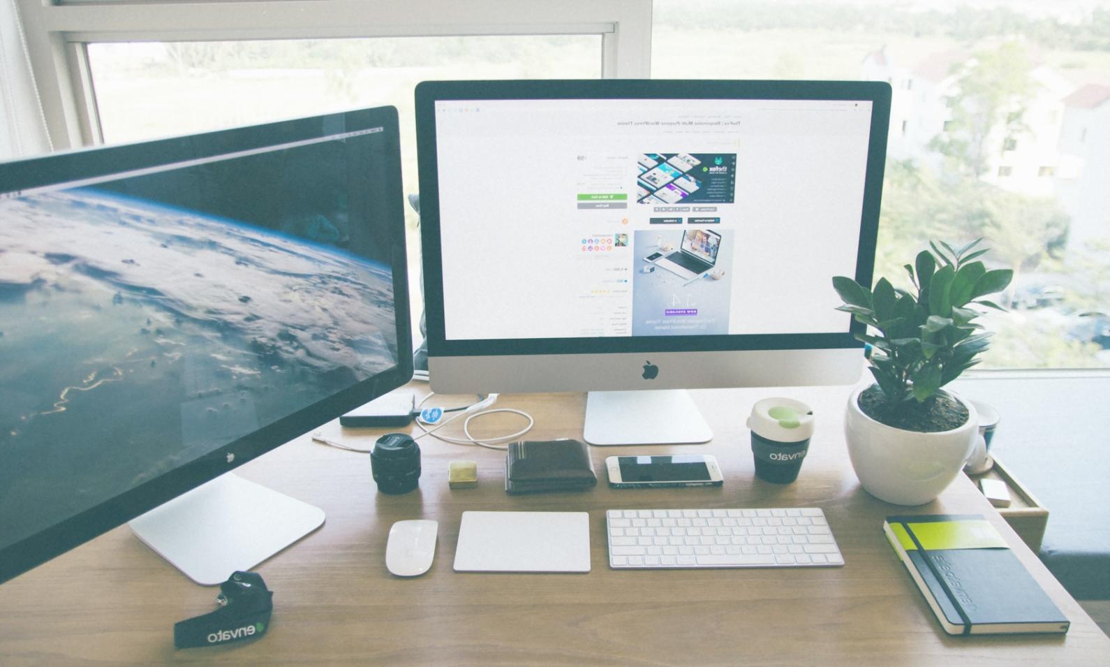 Professional web development workspace showing multiple monitors with code and design mockups